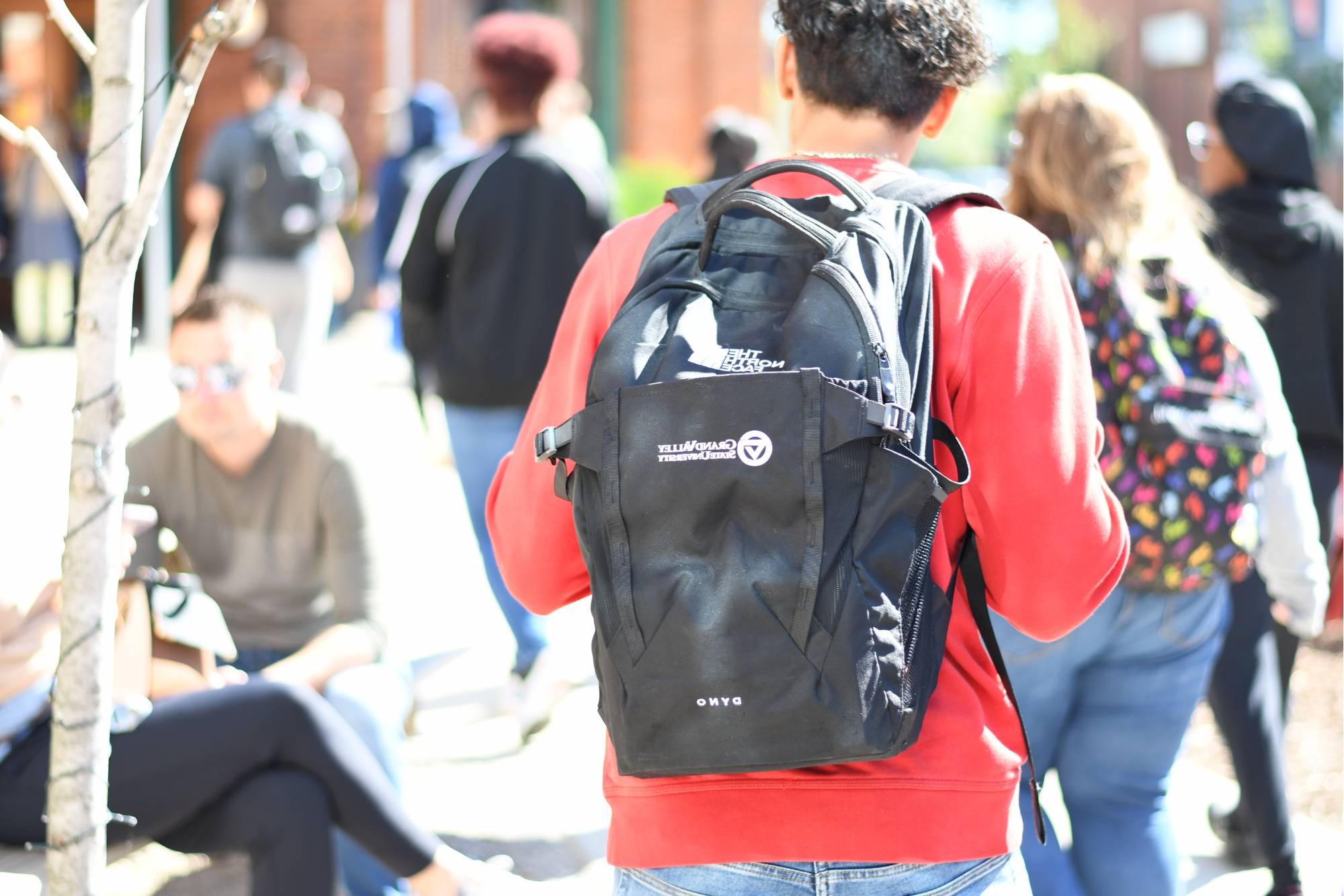 photo of student walking with Grand Valley State University backpack on through a crowd